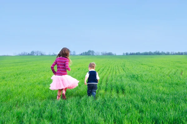 Sestra spouštění s její brather v trávě — Stock fotografie