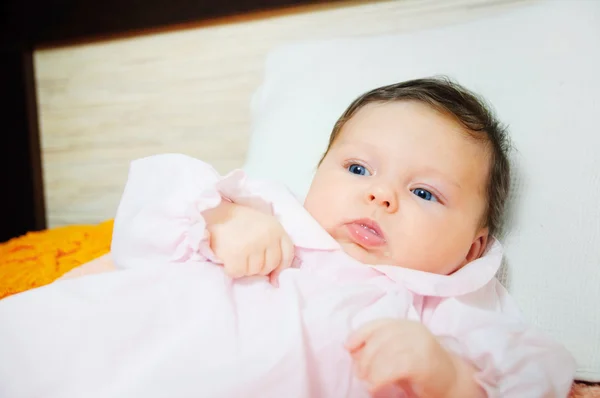 Mooie babymeisje ligt in een bed. — Stockfoto