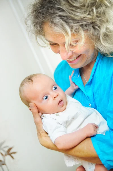 Happy cute infant lying on his grandmother hands — Stock Photo, Image