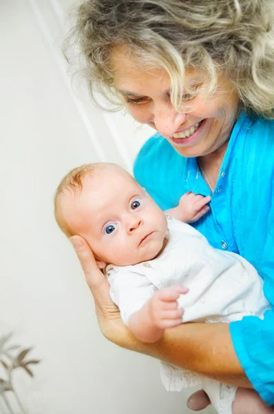 Happy cute infant lying on his grandmother hands — Stock Photo, Image
