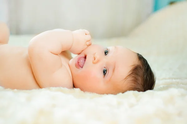 Mooie babyjongen ligt in een bed. — Stockfoto