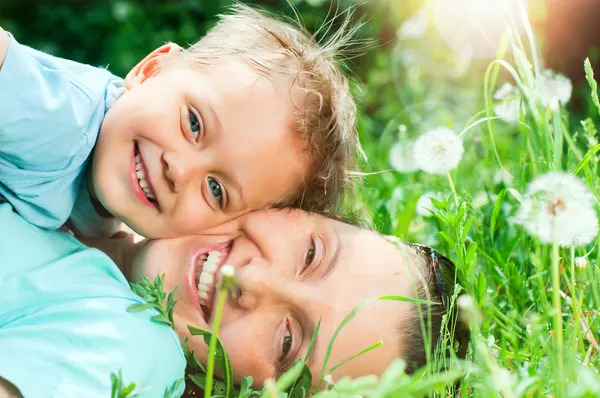 Cute boy with mother lying in the grass — Stock Photo, Image