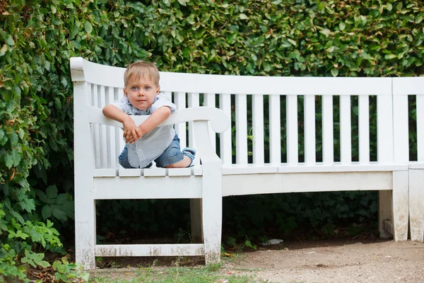 Little boy sits on a bench in a park — Stock Photo, Image