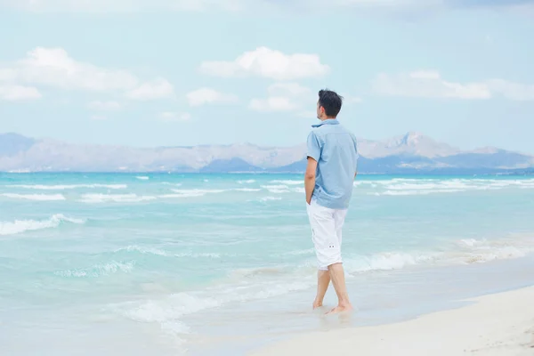 Giovane uomo a piedi vicino al mare blu . — Foto Stock