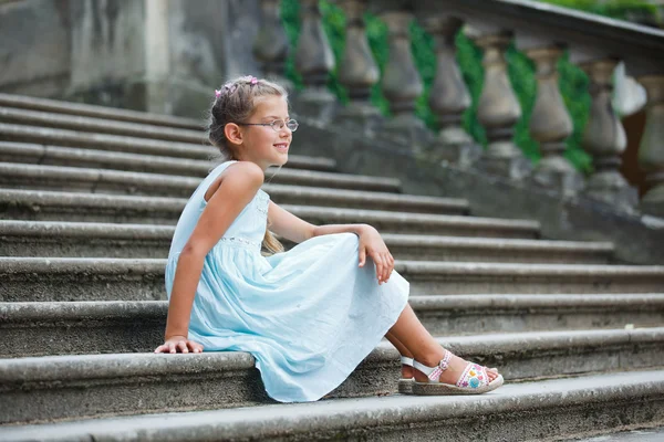 Mooi meisje zit op op de trap in een park — Stockfoto