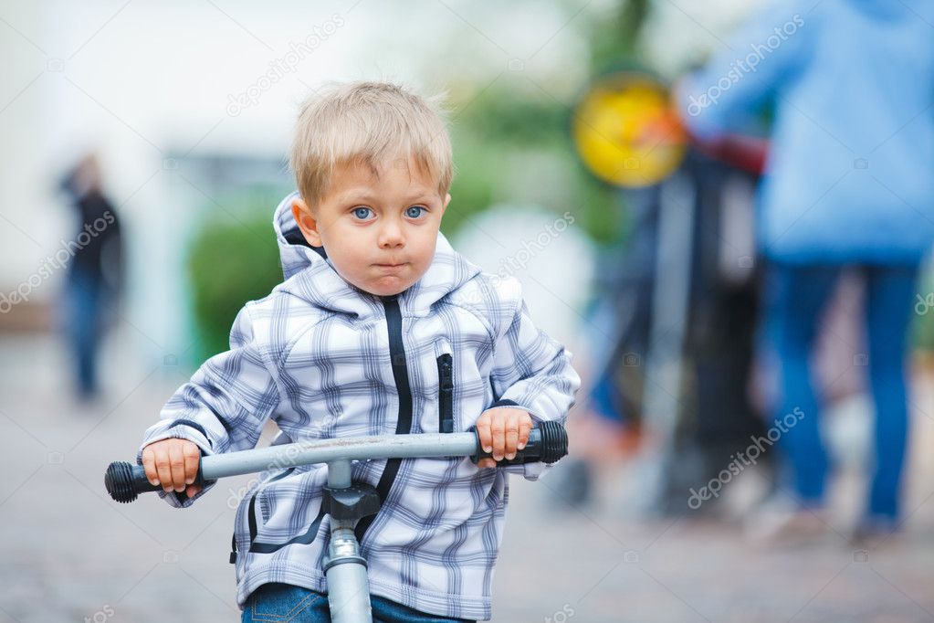 Little cute boy on the bike in city.