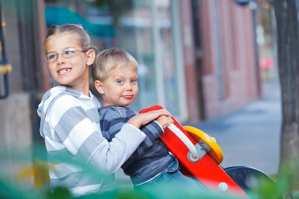 Glada barn rida på gungorna på lekplatsen — Stockfoto