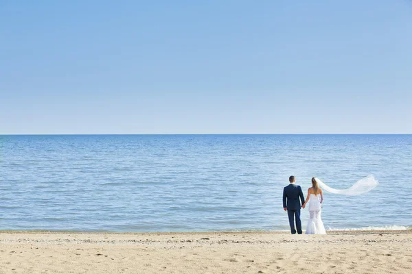 Happy wedding couple standing on beach — Stock Photo, Image