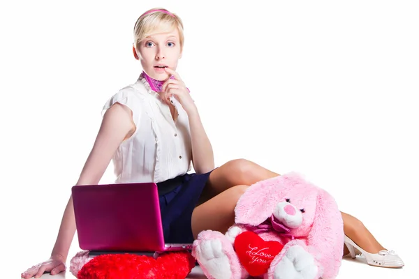 Blond girl working with pink laptop on isolated white — Stock Photo, Image