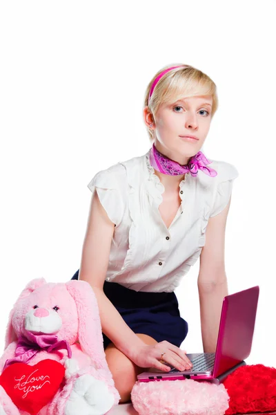 Krásná blondýnka pracující s růžový notebook na izolované bílá — Stock fotografie