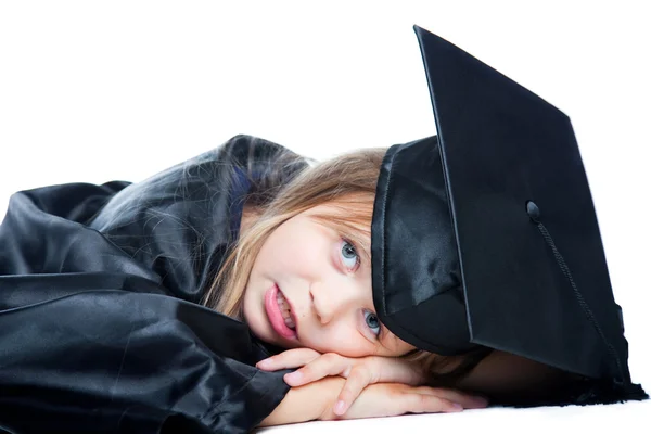 Tired schoolgirl in graduation dress on isolated white — Stock Photo, Image