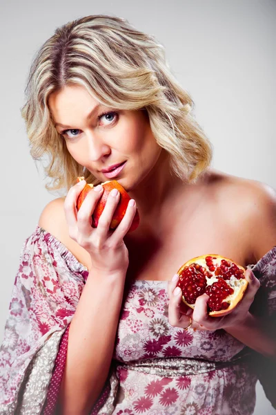 Blonde vrouw met granaatappel op grijs — Stockfoto