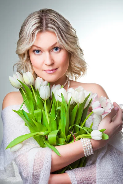 Vacker kvinna med våren tulpaner på grå — Stockfoto