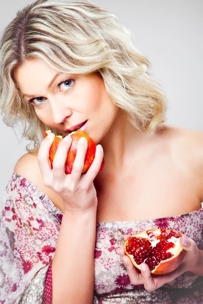 Blonde woman with pomegranate on gray — Stock Photo, Image