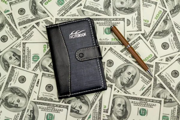 Kladblok met geld en pen — Stockfoto