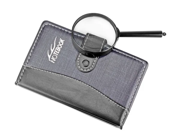 Notebook con una lente d'ingrandimento su di esso isolato su bianco — Foto Stock