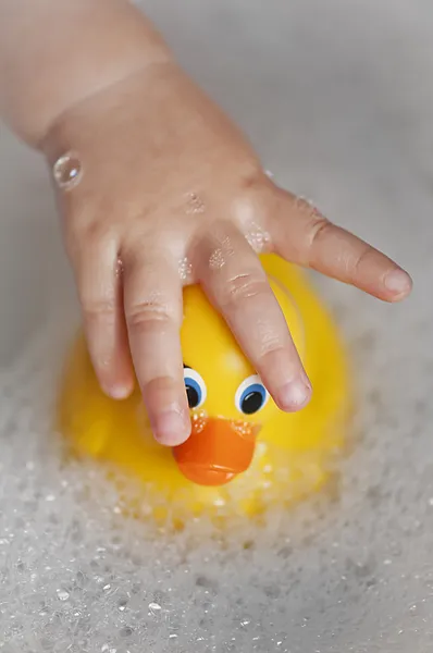Kleinkind badet mit einer Gummiente — Stockfoto