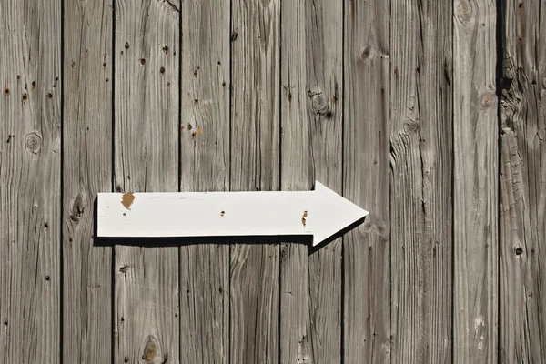 Old weathered wall or fence with wooden arrow sign Stock Picture
