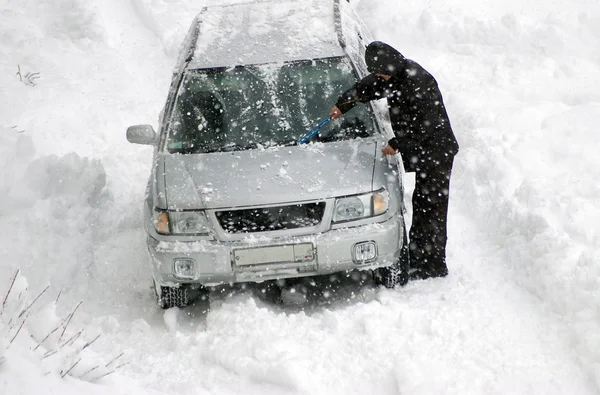 Человек очищает машину от снега — стоковое фото