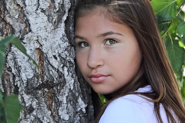 Retrato de uma menina por uma árvore no verão — Fotografia de Stock