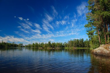 A wilderness lake and summer skies clipart