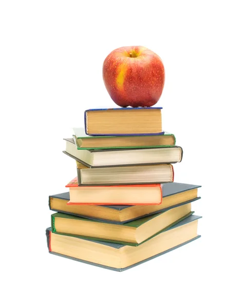 Большое красное яблоко лежит на куче книг — стоковое фото