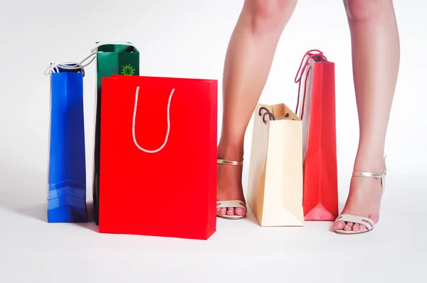 Pernas de mulher e sacos de compras — Fotografia de Stock