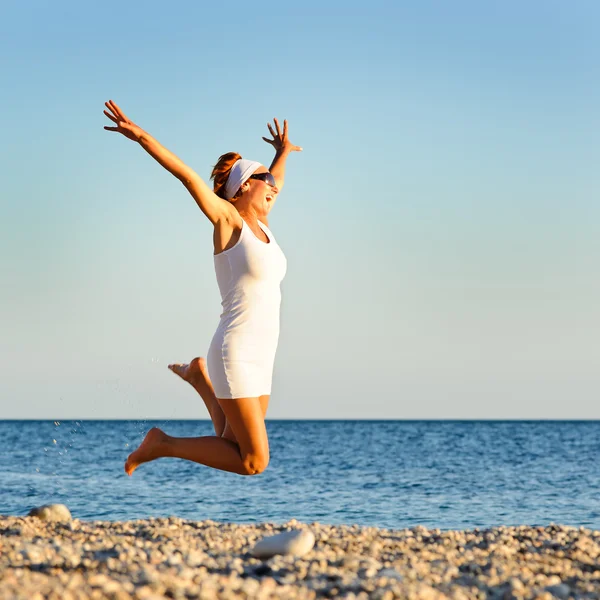 Счастливая молодая женщина прыгает на пляже — стоковое фото