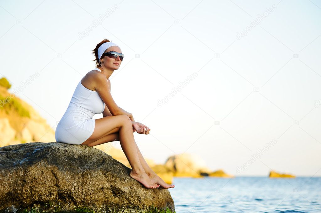Woman sitting on a stone in the sea