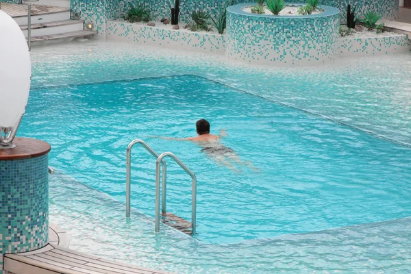 Человек плавает в голубой воде бассейна — стоковое фото