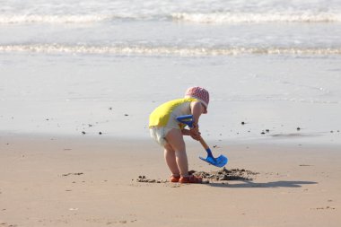 Plajın kumları üzerinde bir kürek ile oynayan genç çocuk