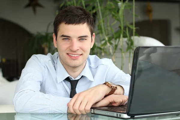 Uomo d'affari a tavola con computer portatile in carica. Sorridi. Denti bianchi — Foto Stock