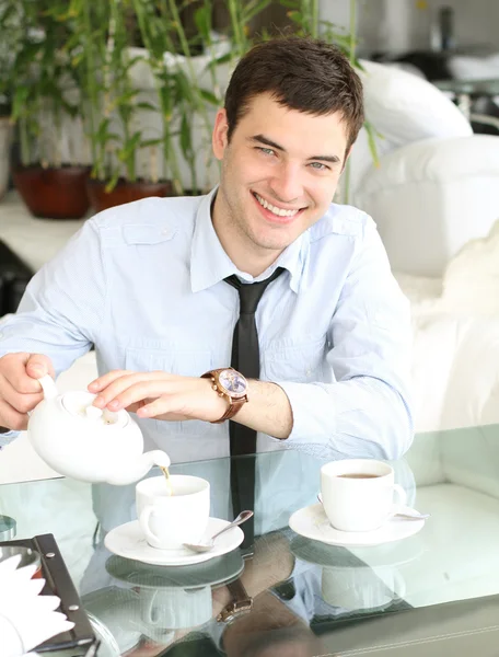 Uśmiechający się młodych ludzi wylewa herbatę do filiżanki — Zdjęcie stockowe
