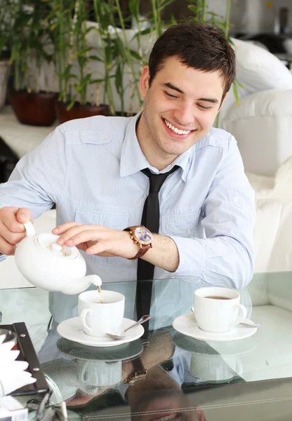 Leende unga män häller te i en kopp. vackert leende — Stockfoto