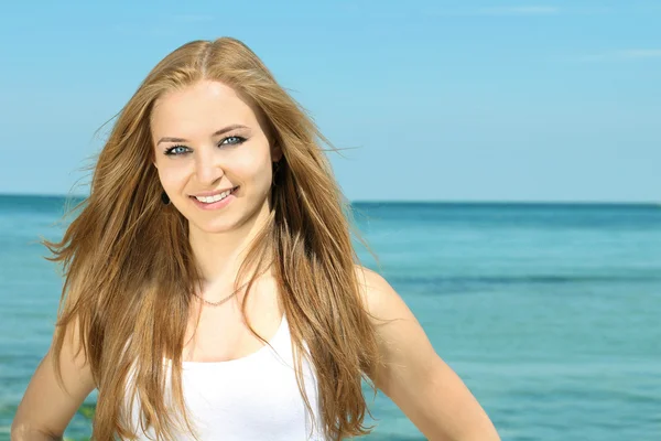 Portréja egy gyönyörű mosolygó fiatal hölgy a strand háttérb — Stock Fotó