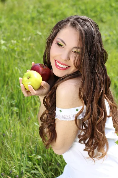 Happy smiling young woman present apples on the nature — Stock Photo, Image