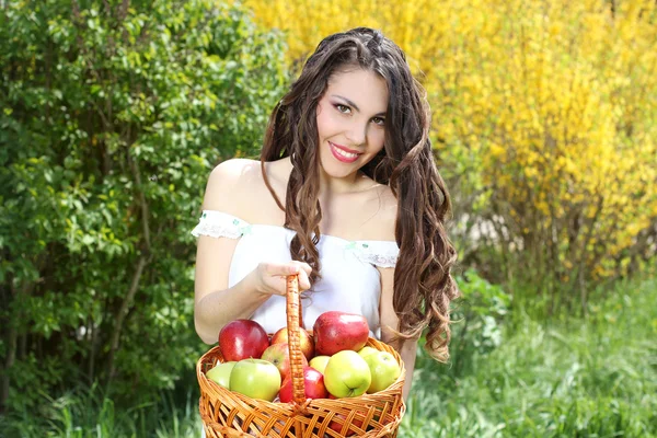Menina em vestido branco apresenta cesta de maçãs — Fotografia de Stock