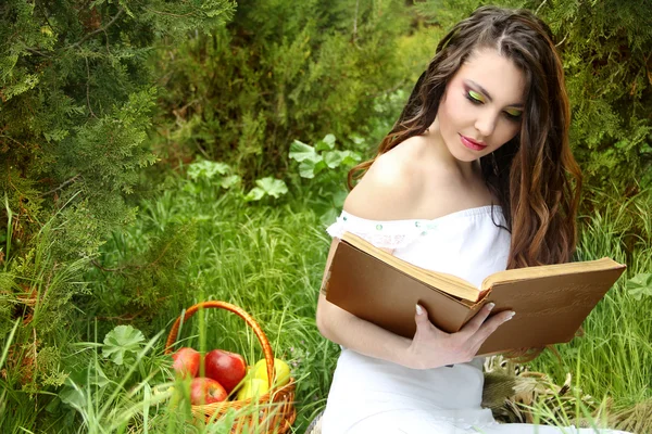 Όμορφη κοπέλα σε πράσινο φόντο και διαβάσει το βιβλίο. — Φωτογραφία Αρχείου