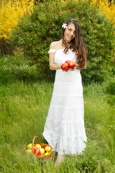 Piękna dziewczyna z koszem w białej sukni gospodarstwa czerwone jabłko — Zdjęcie stockowe