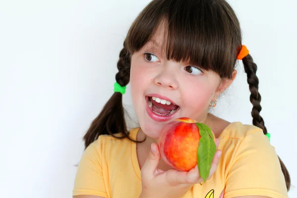 Glimlachend meisje met perzik geïsoleerd op witte achtergrond — Stockfoto