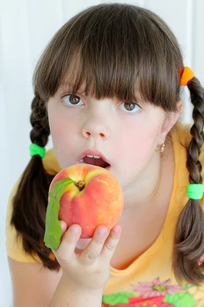 Krásná mladá dívka, jíst pomerančovou broskev — Stock fotografie