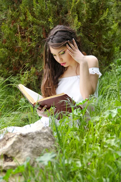 Ung vacker tjej läser en bok utomhus — Stockfoto