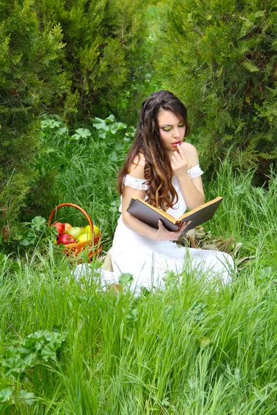 Jovem menina bonita lendo um livro ao ar livre — Fotografia de Stock