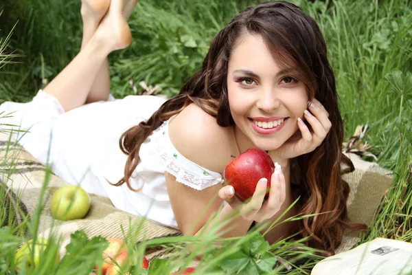 Porträtt en ganska unga kvinnor med rött äpple på det gröna fältet — Stockfoto