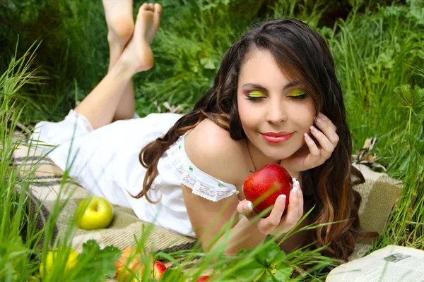 Retrato de una hermosa mujer joven con manzana roja en el campo verde —  Fotos de Stock