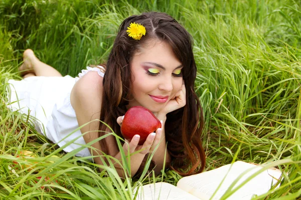 Ritratto una bella giovane donna con mela rossa sul campo verde — Foto Stock