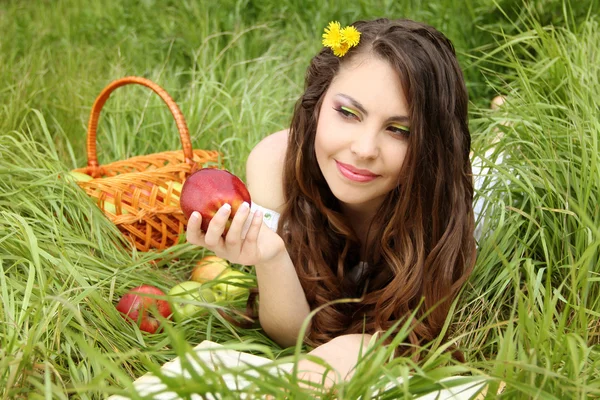 Retrato de una hermosa mujer joven con manzana roja en el campo verde — Foto de Stock