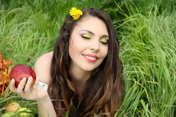 Retrato de una hermosa mujer joven con manzana roja en el campo verde —  Fotos de Stock