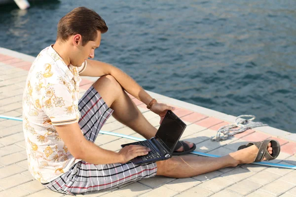 Όμορφος επιχειρηματίας που τρέχει ένα φορητό υπολογιστή στην ακτή κοντά την yach — Φωτογραφία Αρχείου