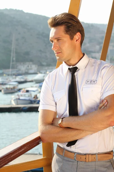 Bonito homem com uma camisa branca olhando para longe, sol ao ar livre, porto do mar — Fotografia de Stock
